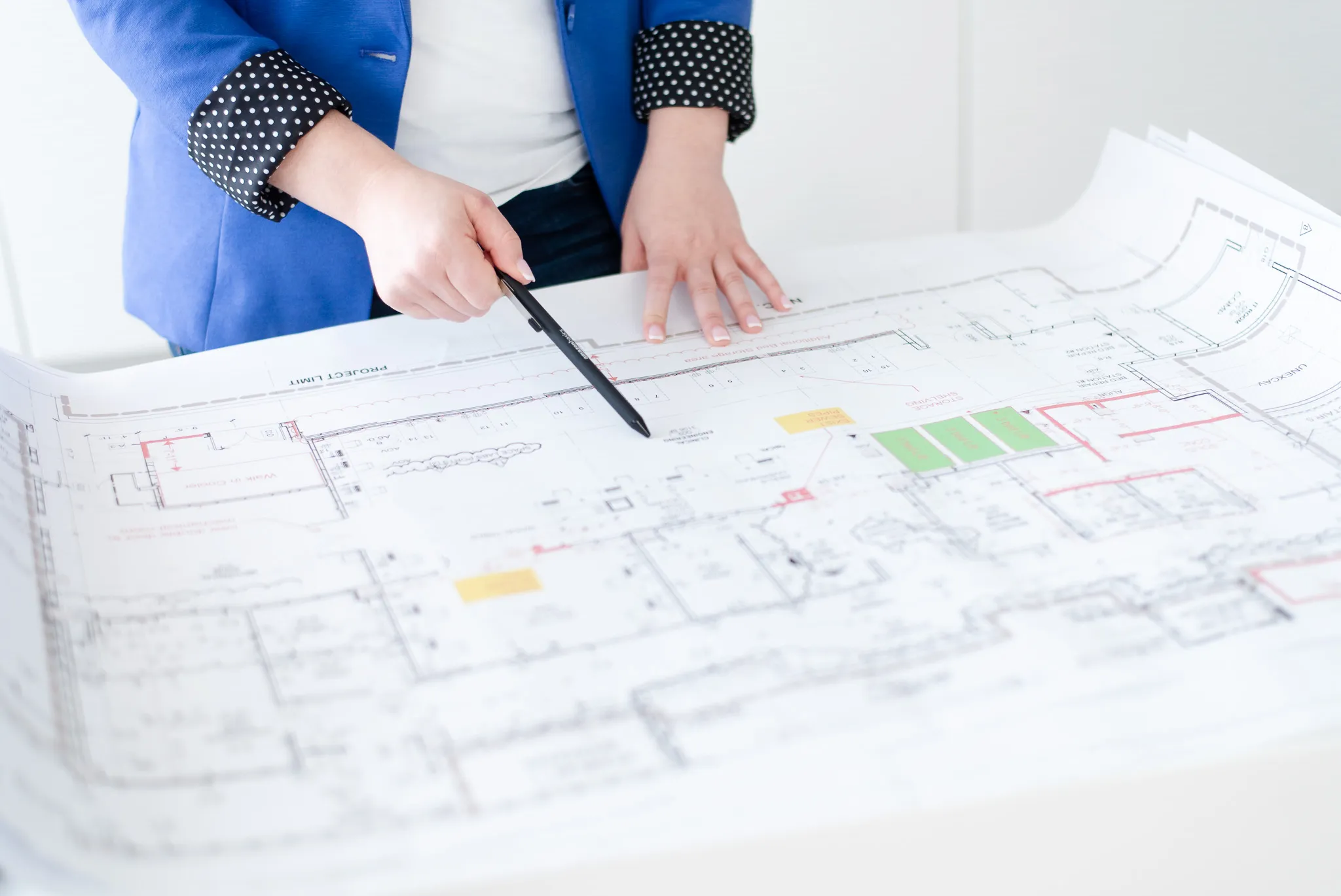 Hands Holding a Pen Pointing at a Blueprint