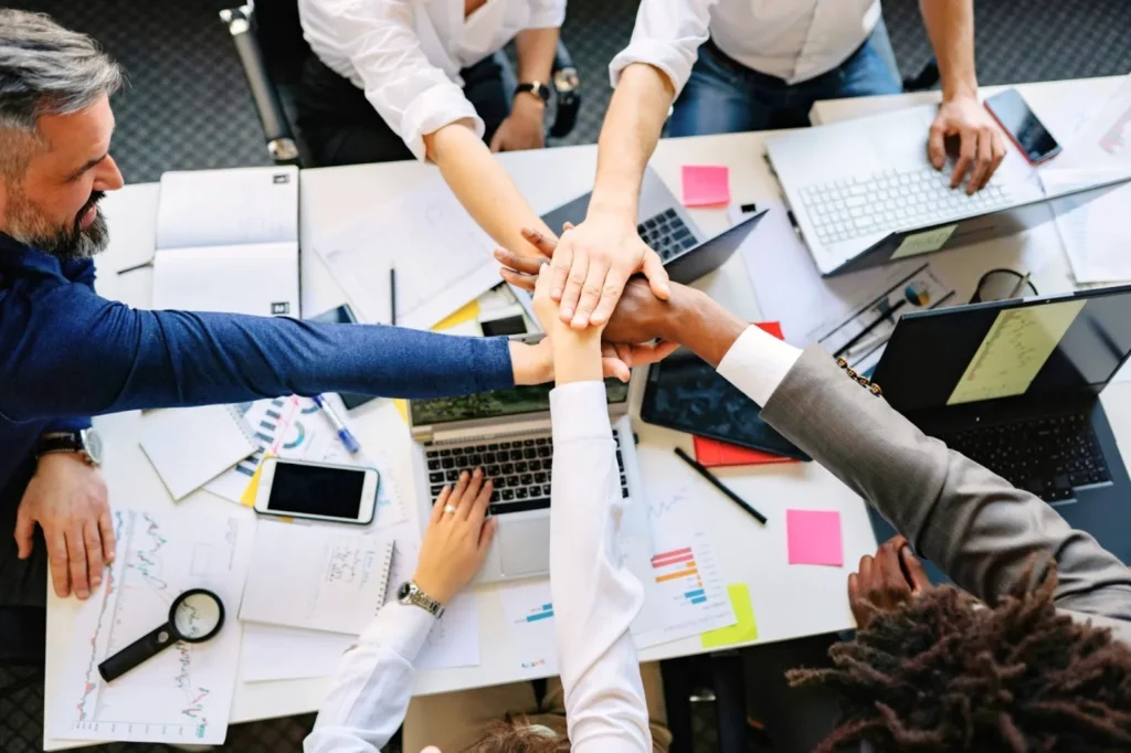 Team Stacking Hands Over Conference Table in Collaboration