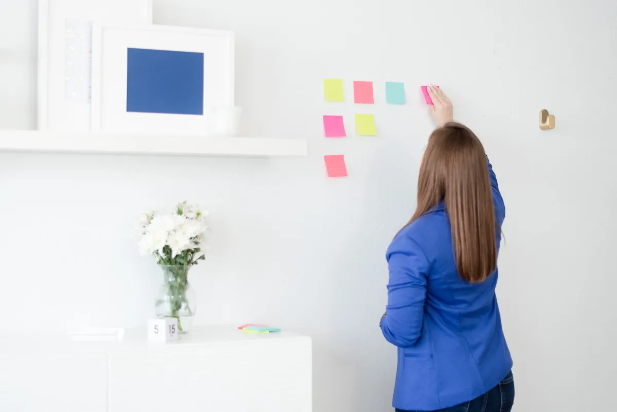 Whitney-WGB-Outsource-Project-Management Back of Whitney Aligning Sticky Notes on a Wall