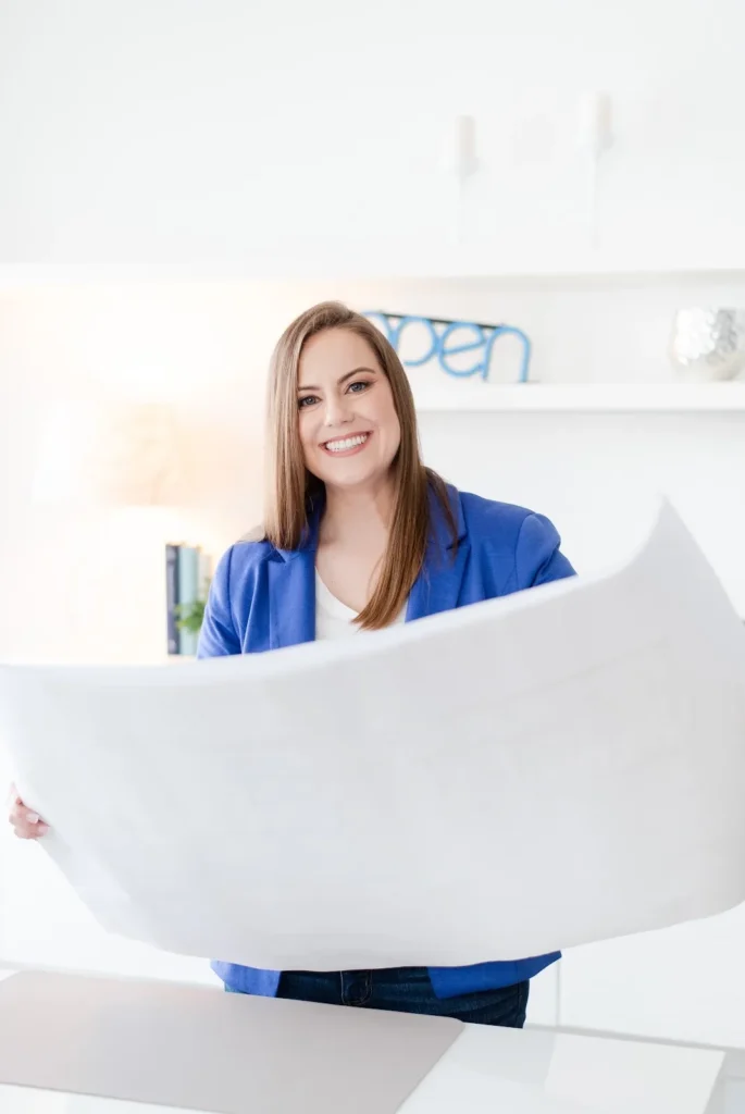 Whitney (COO) Holding Blueprint at Desk