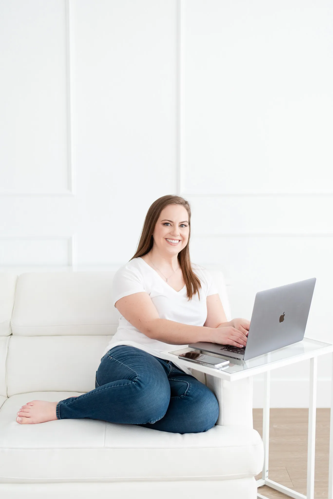 Whitney Typing Policies on Laptop Sitting on White Couch