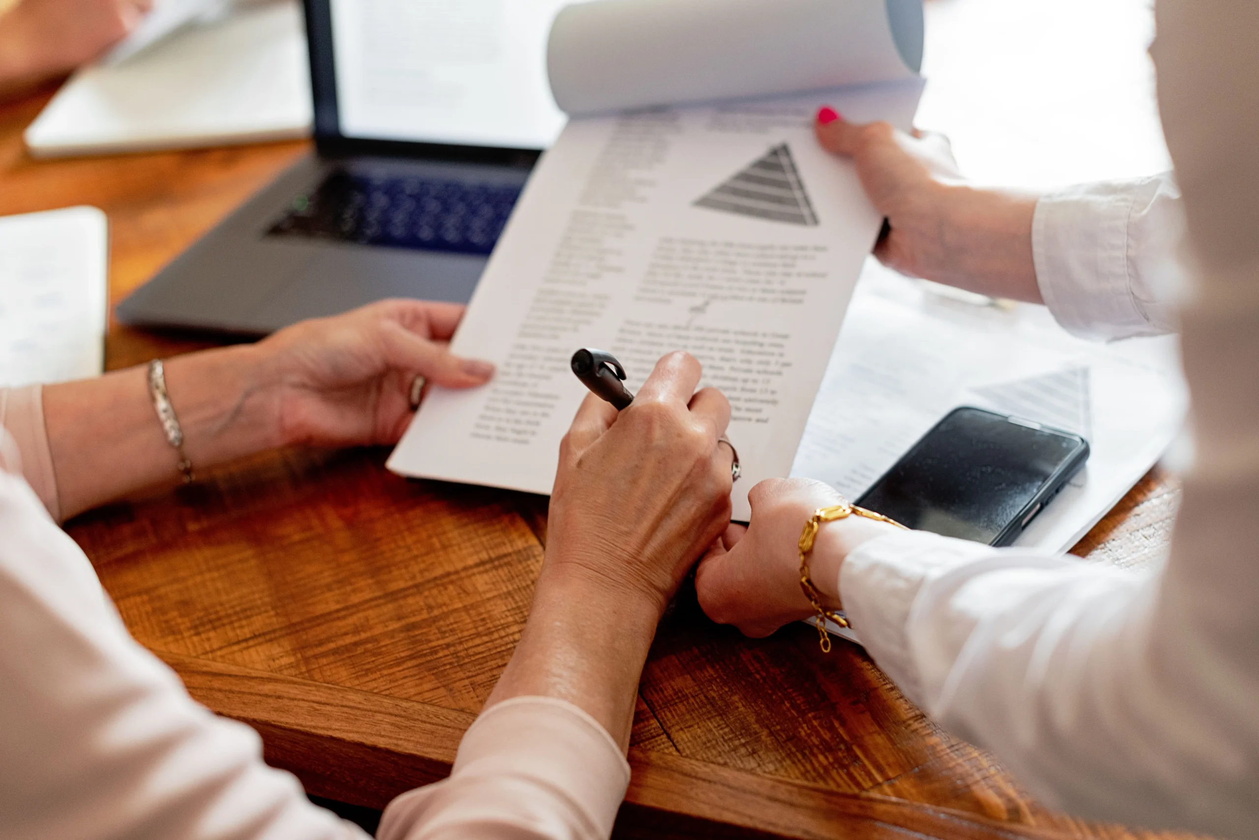 Hands of Two Women Reviewing Documents at Desk Hands of Two Women Reviewing Documents at Desk