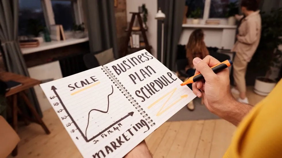 Person Holds Notebook of Business Plan Schedule